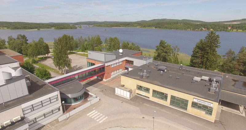 Kuvassa Nurmeksen lukion ja ammattiopisto Riverian muodostama kampusalue, jonka takaa avautuu Nurmesjärven kesäinen rantamaisema.
