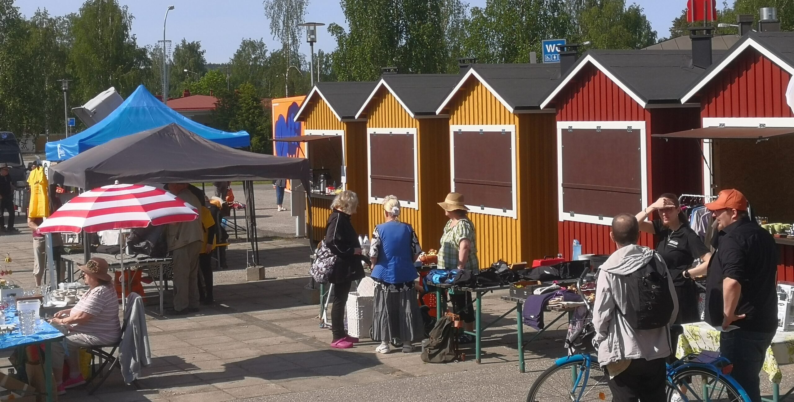 Kuva kauppatorilta, torikojuja ja ihmisiä